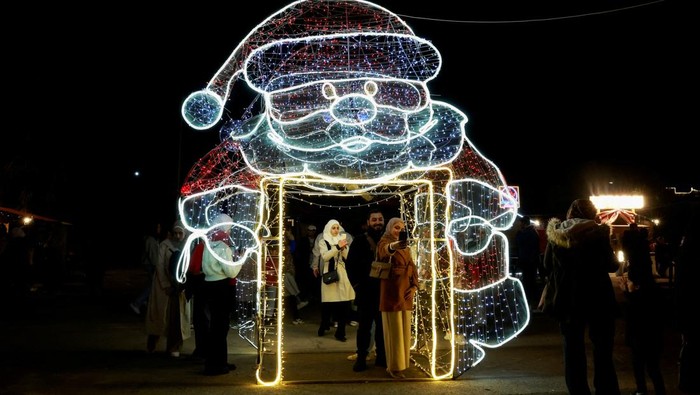 People pose for pictures by Christmas decorations in Damascus, after Syria's Bashar al-Assad was ousted, in Damascus, Syria December 19, 2024. REUTERS/Ammar Awad