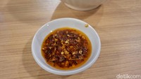 Jika ingin menyantap laksanya lebih pedas, ada chilli oil yang disiapkan. Pelanggan bisa mengaduknya ke dalam kuah untuk rasa gurih yang lebih menggelitik pedasnya. Foto: detikcom/Diah Afrilian