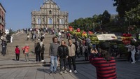 Pengunjung berfoto di depan Reruntuhan St. Paul menjelang perayaan ulang tahun ke-25 penyerahan Makau ke pemerintahan China, di Makau, Kamis (19/12/2024). (AP Photo/Anthony Kwan)