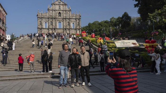 Visitors pose for a photo in front of the Ruins of St. Paul's ahead of celebrations for the 25th anniversary of Macao's handover to Chinese rule, in Macao, Thursday, Dec. 19, 2024. (AP Photo/Anthony Kwan)