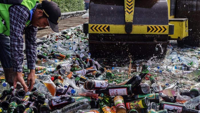 Petugas memusnahkan botol minuman keras (miras)  di  Cibinong, Kabupaten Bogor, Jawa Barat, Jumat (20/12/2024). Polres Bogor memusnahkan barang bukti berbagai jenis miras sebanyak 15.250 botol dalam rangka operasi Lilin Lodaya 2024  jelang Natal dan Tahun Baru 2025. ANTARA FOTO/Yulius Satria WIjaya/Spt.