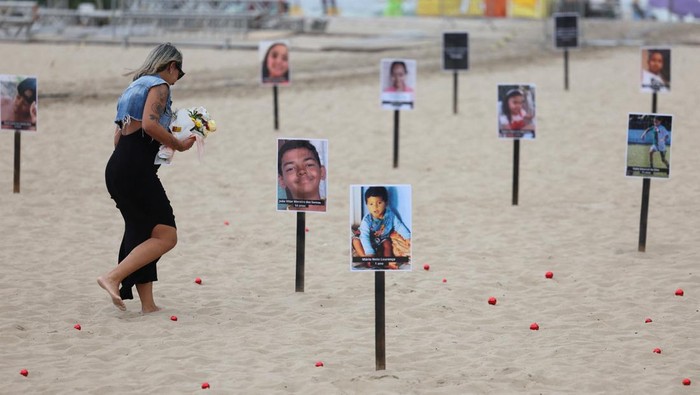 A woman runs past 48 pictures of children who were shot dead during police operations during the administration of Rio de Janeiro's governor Claudio Castro, by NGO Rio de Paz, at Copacabana beach in Rio de Janeiro, Brazil December 18, 2024. REUTERS/Pilar Olivares