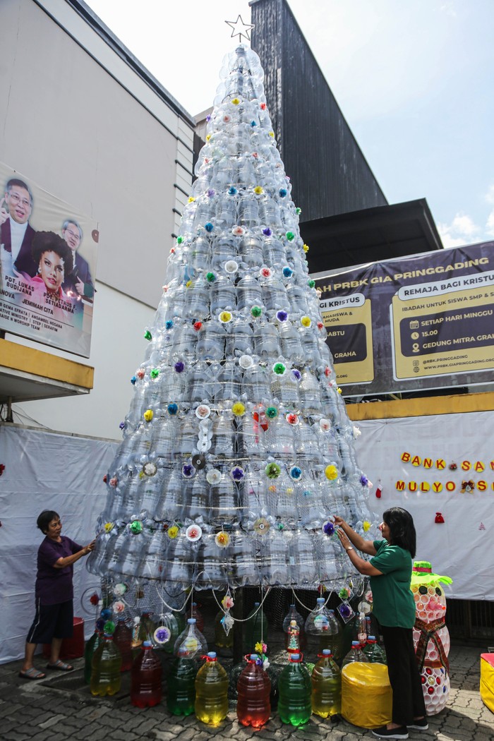 Dua anggota kelompok Bank Sampah Mulyo Sedoyo merapikan pernak-pernik hiasan dekorasi pohon natal yang terbuat dari bahan limbah plastik di halaman Gedung Mitra Graha, Semarang, Jawa Tengah, Jumat (20/12/2024). Dekorasi pohon natal dengan tinggi tujuh meter yang dibuat dari 280 galon plastik dan 25 botol plastik bekas tersebut diinisiasi kelompok wanita Bank Sampah Mulyo Sedoyo untuk menyambut perayaan Hari Raya Natal 2024 sekaligus mengkampanyekan pelestarian lingkungan melalui pemanfaatan daur ulang sampah plastik.