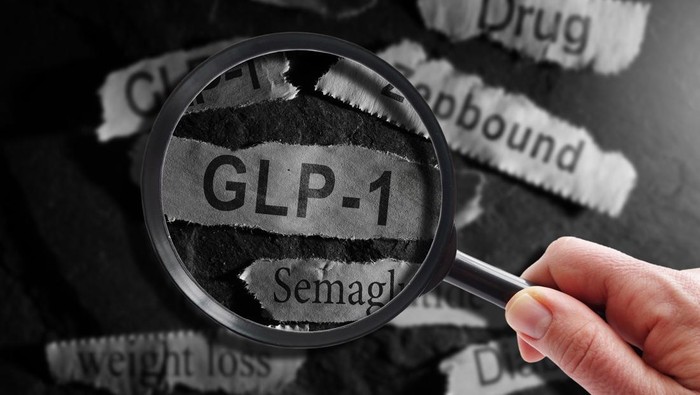 Raleigh, NC - USA - 06-13-2024: GLP-1 related drugs newspaper headlines with hand and magnifying glass