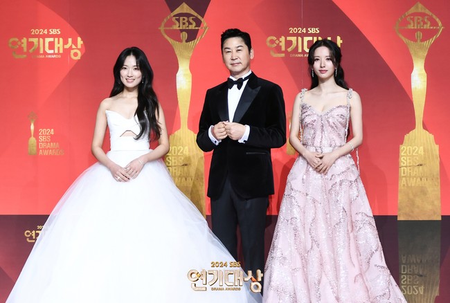 Dua aktris cantik, Kim Hye Yoon dan Bona WJSN menjadi pemandu acara SBS Drama Awards 2024 bersama Shin Dong Yup. Kim Hye Yoon tampil memakai gaun putih dengan aksen cutout pada bagian torso. Sedangkan Bona WJSN mengenakan gaun berwarna pink dengan detail payet. Foto: dok. SBS