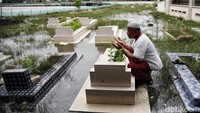 Seorang warga berdoa di makam yang tak pernah kering karena terendam banjir rob.