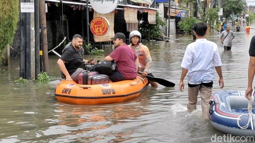 Turis dievakuasi menggunakan perahu karet karena banjir merendam di kawasan Dewi Sri, Legian, dan sekitarnya, Minggu (22/12/2024).