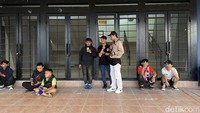 Sejumlah penonton menunggu pintu gate stadion dibuka sekaligus berteduh dari air hujan yang mulai turun.
