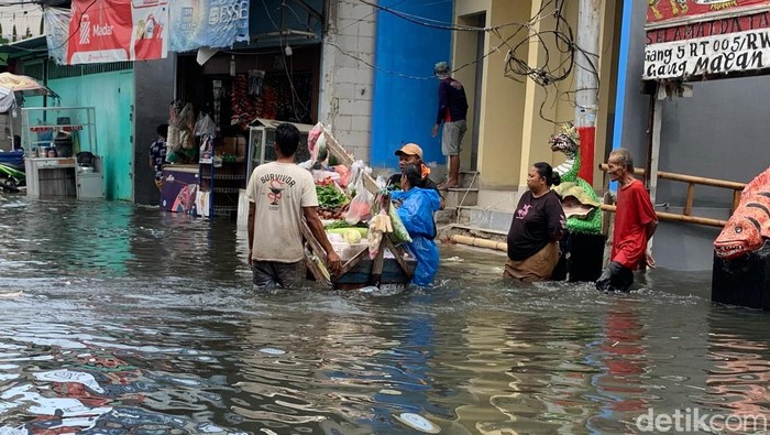 Penjual sayur keliling menjajakan dagangannya di tengah banjir rob Muara Angke, Selasa (17/12/2024). Natasya Oktavia Raymond (magang detikX