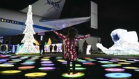 Seorang anak bermain di antara lampu-lampu liburan bertema luar angkasa di dekat replika pesawat ulang-alik Independence di Space Center Houston. AP/Ashley Landis