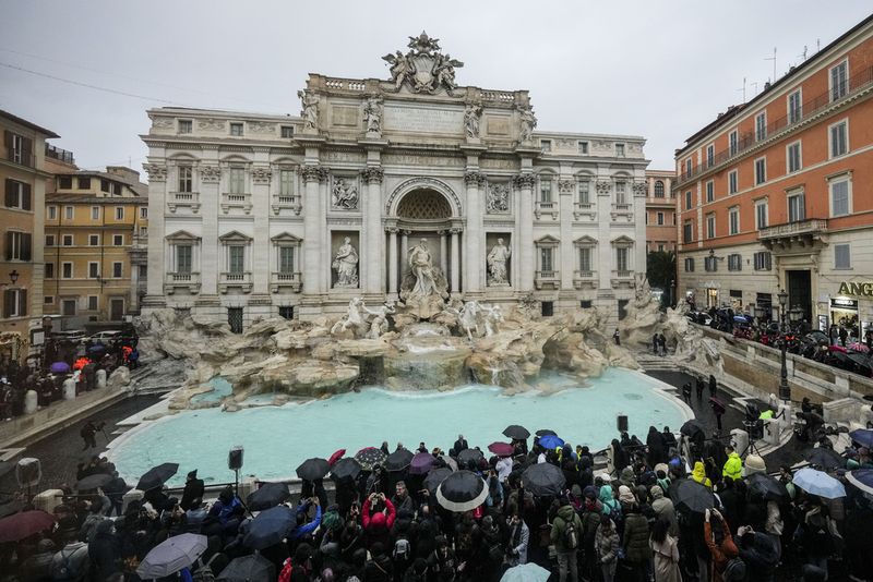 People admire the 18th century Trevi Fountain, one of Rome's most iconic landmarks, as it reopens to the public after undergoing maintenance, just on time for the start of the Jubilee Year, an event expected to draw millions of visitors to the Eternal City, in Rome, Sunday, Dec. 22, 2024. (AP Photo/Andrew Medichini)