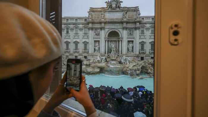 People admire the 18th century Trevi Fountain, one of Rome's most iconic landmarks, as it reopens to the public after undergoing maintenance, just on time for the start of the Jubilee Year, an event expected to draw millions of visitors to the Eternal City, in Rome, Sunday, Dec. 22, 2024. (AP Photo/Andrew Medichini)