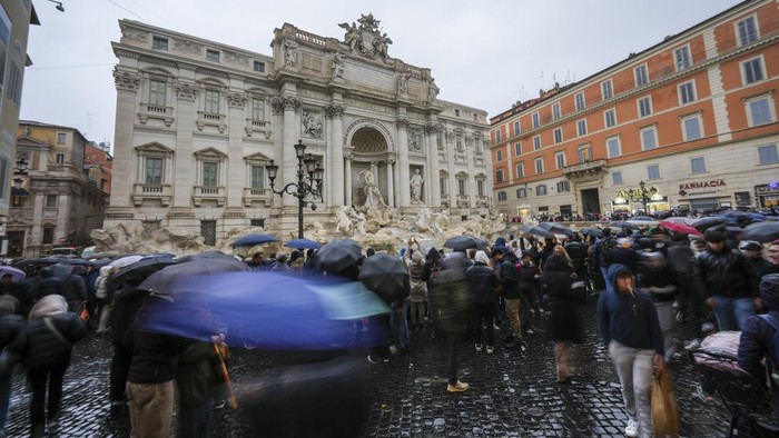 People admire the 18th century Trevi Fountain, one of Rome's most iconic landmarks, as it reopens to the public after undergoing maintenance, just on time for the start of the Jubilee Year, an event expected to draw millions of visitors to the Eternal City, in Rome, Sunday, Dec. 22, 2024. (AP Photo/Andrew Medichini)