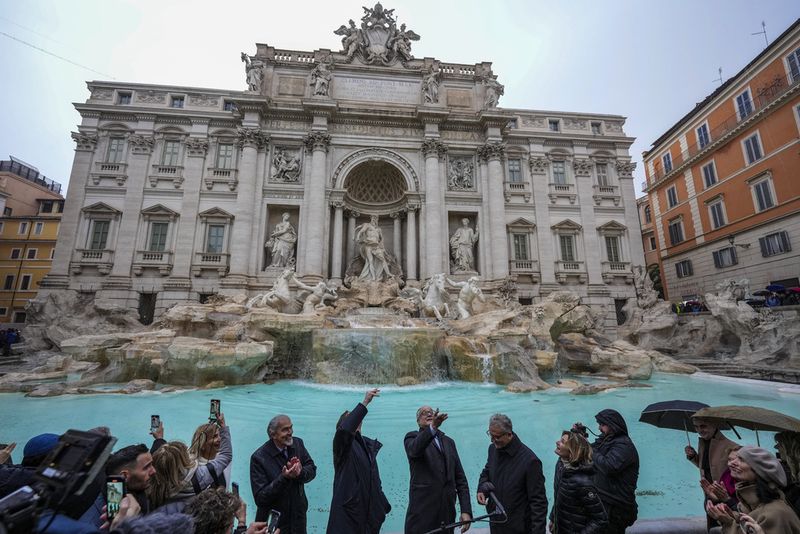 People admire the 18th century Trevi Fountain, one of Rome's most iconic landmarks, as it reopens to the public after undergoing maintenance, just on time for the start of the Jubilee Year, an event expected to draw millions of visitors to the Eternal City, in Rome, Sunday, Dec. 22, 2024. (AP Photo/Andrew Medichini)