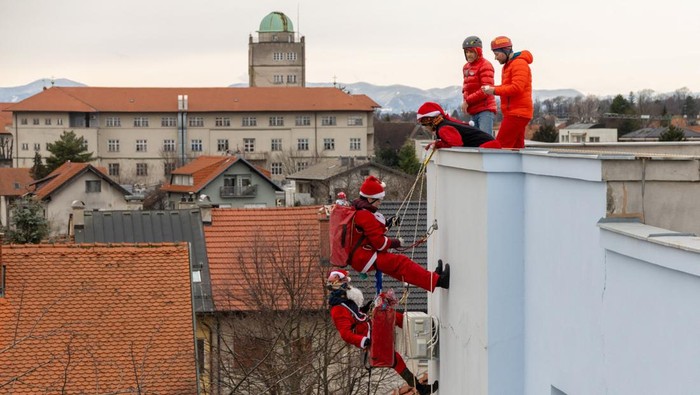 A drone view shows volunteers, dressed in Santa Claus costumes, rappelling from the roof of Children's Hospital Srebrnjak to bring gifts to the children, in Zagreb, Croatia December 23, 2024. REUTERS/Antonio Bronic