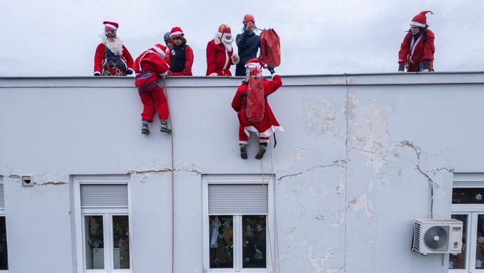 A drone view shows volunteers, dressed in Santa Claus costumes, rappelling from the roof of Children's Hospital Srebrnjak to bring gifts to the children, in Zagreb, Croatia December 23, 2024. REUTERS/Antonio Bronic