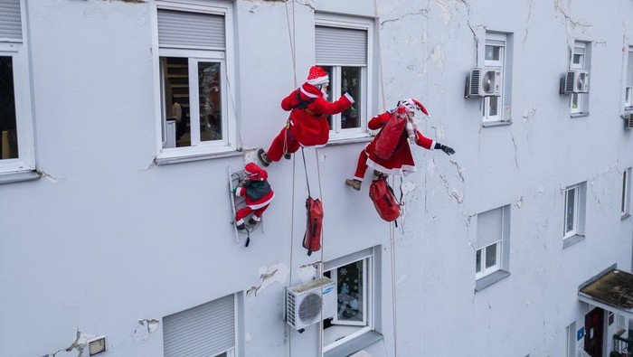 A drone view shows volunteers, dressed in Santa Claus costumes, rappelling from the roof of Children's Hospital Srebrnjak to bring gifts to the children, in Zagreb, Croatia December 23, 2024. REUTERS/Antonio Bronic