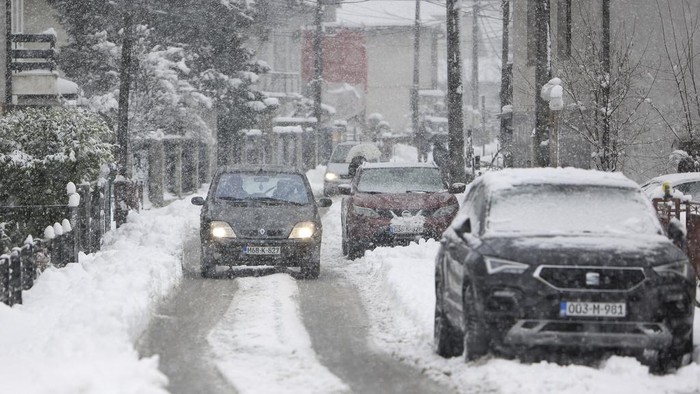 A car drives down the street during heavy snowfall in Bihac, Bosnia, Monday, Dec. 23, 2024. (AP Photo/Edvin Zulic)