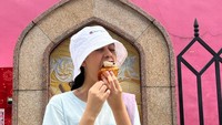 Salah satu posenya dengan latar sebuah bangunan tampak menarik. Ia tengah menikmati cupcake yang lezat. Foto: Instagram @therealasilamaisa