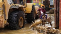 Warga berusaha membuang air dari rumahnya yang tergenang banjir.  