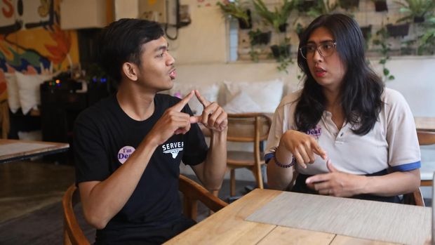 Dua pekerja penyandang tuli di Inklusiv Warung, Yogi Satya dan Iyam, tengah berbincang menggunakan bahasa isyarat, Senin (9/12/2024).