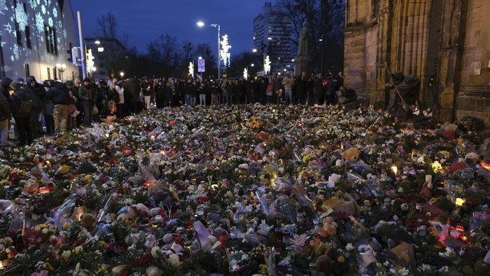 People hold canddles in memory of the victims and those affected by the attack at the Magdeburg Christmas market on Friday evening, in Magdeburg, Germany, Monday, Dec. 23, 2024. (Sebastian Willnow/dpa via AP)