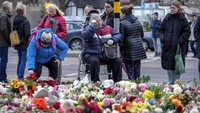 Orang-orang meletakkan bunga dan lilin di depan gereja Johannis dekat pasar Natal tempat sebuah mobil menabrak kerumunan pada Jumat malam, di Magdeburg, Jerman, Senin (23/12/2024).  