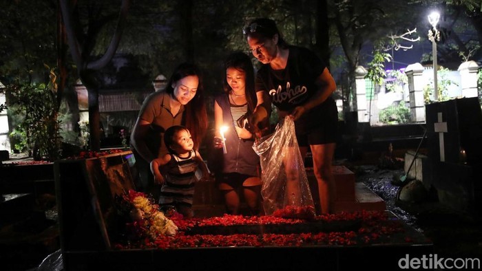 Tradisi Ziarah Kubur Warga Keturunan Portugis Warga keturunan Portugis berdoa saat melakukan ziarah di makam keluarganya pada malam Natal di kawasanΒ Gererja Protestan Indonesia Barat Tugu, Semper Barat, Jakarta Utara, Selasa (24/12/2024).