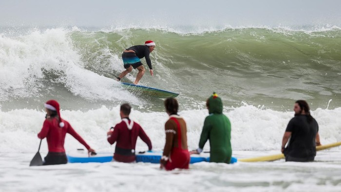 A surfer dressed as Santa places a plastic reindeer on the front of his board at the annual Surfing Santas Christmas Eve event in Cocoa Beach, Florida, U.S. December 24, 2024. REUTERS/Sam Wolfe TPX IMAGES OF THE DAY