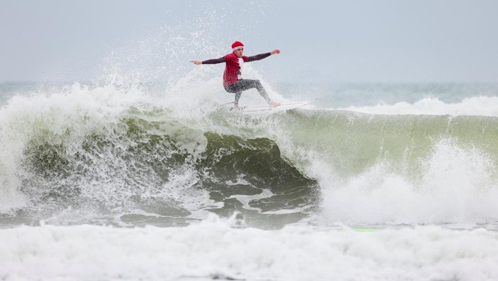 A surfer dressed as Santa places a plastic reindeer on the front of his board at the annual Surfing Santas Christmas Eve event in Cocoa Beach, Florida, U.S. December 24, 2024.  REUTERS/Sam Wolfe     TPX IMAGES OF THE DAY