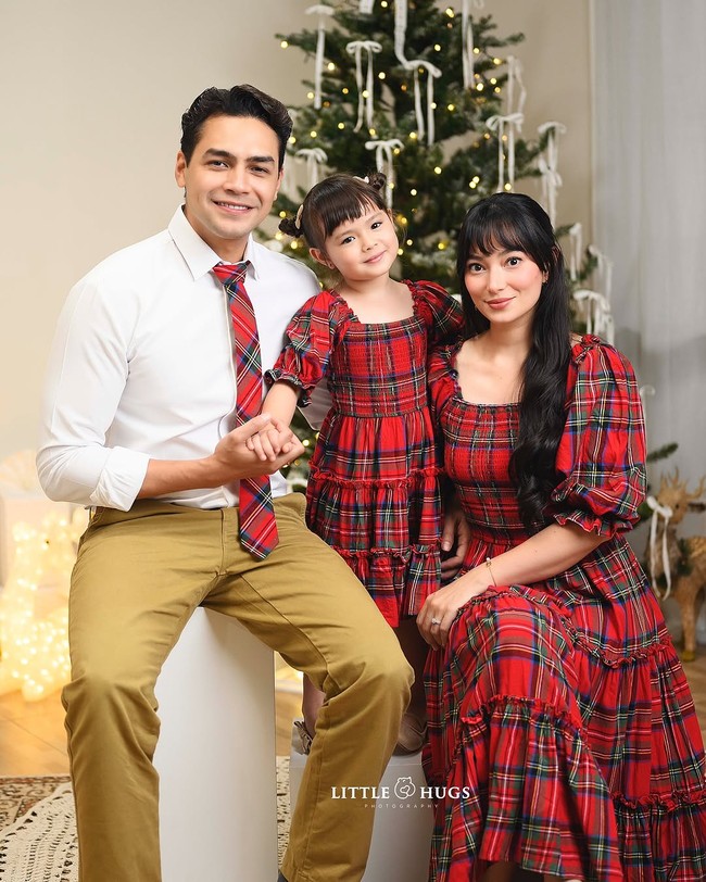 Keluarga Asmirandah dan Jonas Rivanno menampilkan semangat Natal dengan busana motif tartan warnah merah-hitam. Tampak pohon Natal dengan desain simple berhias pita dan lampu sebagai dekorasi yang mempercantik rumah. Foto: Dok. Instagram