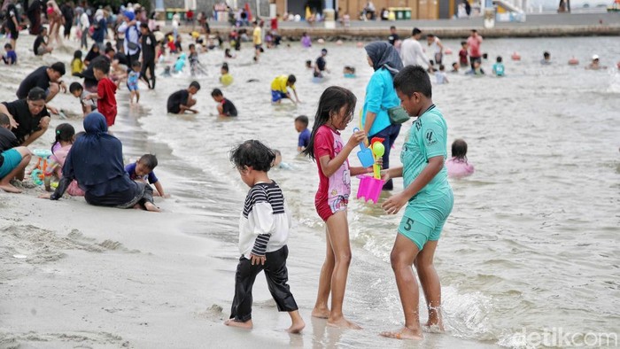Sejumlah pengunjung menikmati suasana pantai di kawasan Ancol Taman Impian, Jakarta Utara, Rabu (25/12/2024). Menurut keterangan pengelola Ancol data pengunjung saat liburan Natal mencapai 20.000 pada jam 12.00 WIB.