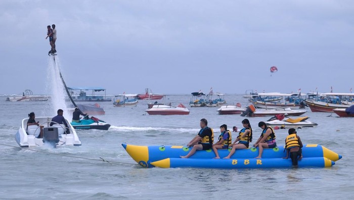 Wisatawan bermain wahana banana boat di Pantai Tanjung Benoa, Kuta Selatan, Badung, Bali, Rabu (25/12/2024). Kunjungan wisata di pantai yang terkenal dengan wahana water sport tersebut didominasi wisatawan nusantara pada liburan Natal. ANTARA FOTO/Nyoman Hendra Wibowo/wpa.