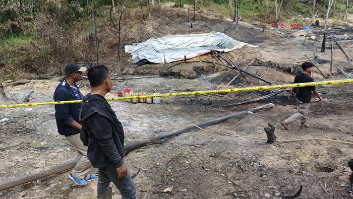 Polisi memasang police line lokasi sumur minyak terbakar di Senami, Batanghari, Jambi