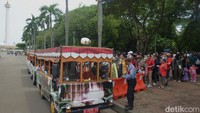 Masyarakat antre untuk naik mobil shuttle di Monas, Jakarta, Kamis (26/12/2024). 