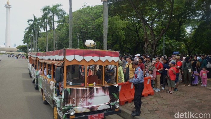 Masyarakat antre untuk naik mobil shuttle di Monas, Jakarta, Kamis (26/12/2024).