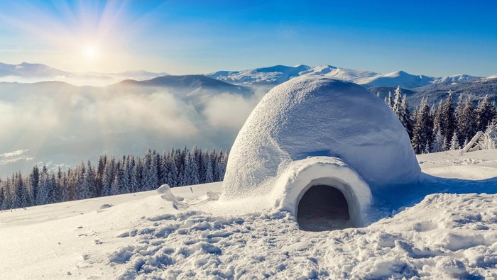 real snow igloo in the mountains under blue sky and sun