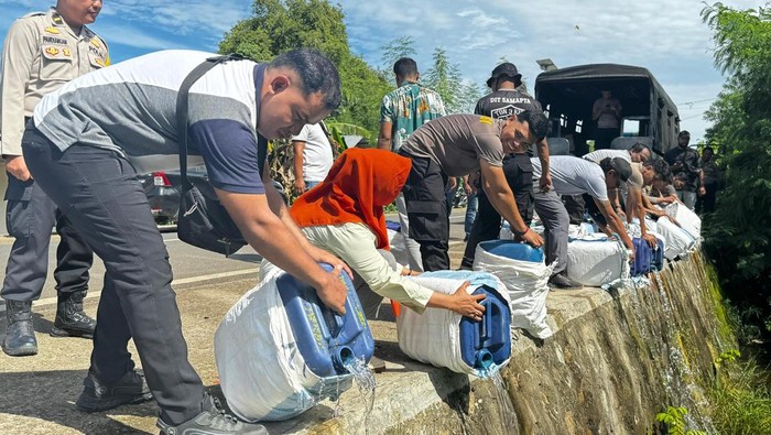 Anggota Polres Manggarai Barat membuang 2.100 liter minuman keras (miras) jenis sopi ilegal ke selokan, Jumat (27/12/3024).