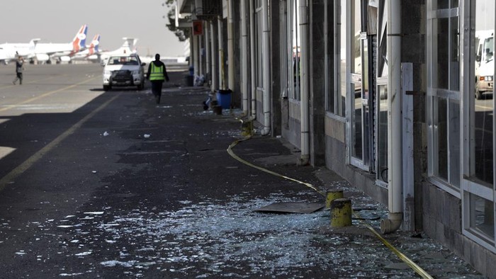 Workers walk past broken glass in Sana'a International Airport following Thursday's Israeli airstrikes on Yemen, Friday, Dec. 27, 2024. The Israeli military reported targeting infrastructure used by the Houthis at the Sanaa International Airport, as well as ports in Hodeida, Al-Salif, and Ras Qantib, along with power stations Thursday Dec. 26..(AP Photo/Osamah Abdulrahman)