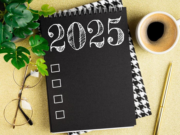 New year resolutions 2025 on desk. 2025 resolutions list with notebook, coffee cup on table. Goals, resolutions, plan, action, checklist concept. New Year 2025 template. Copy space