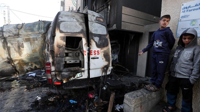 Palestinians stand near the remains of a broadcasting vehicle following an Israeli airstrike that killed five journalists from Al-Quds Al-Youm television channel near Al-Awda Hospital, according to medics with the Gaza health authorities, amid the ongoing conflict between Israel and Hamas in Nuseirat, central Gaza Strip, December 26, 2024. REUTERS/Ramadan Abed     TPX IMAGES OF THE DAY