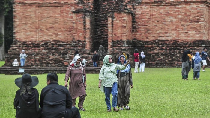 Sejumlah wisatawan mengunjungi Candi Tinggi dalam Kawasan Cagar Budaya Nasional (KCBN) Muarajambi di Muaro Jambi, Jambi, Kamis (26/12/2024). Kawasan situs cagar budaya yang diperkirakan dibangun pada abad ke-6 dan menjadi kawasan pendidikan Buddha terbesar di Asia Tenggara atau seluas 3.981 hektare itu menjadi pilihan sebagian warga untuk memanfaatkan waktu libur Natal 2024 dan Tahun Baru 2025 dengan kunjungan rata-rata per hari 500 orang lebih. ANTARA FOTO/Wahdi Septiawan/YU