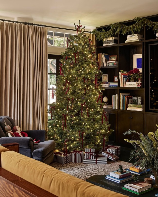 Ia mengajak tur singkat di ruang tamu dan ruang makannya, menampilkan pengaturan meja makan untuk Natal, perapian kayu yang menyala, dan pohon Natal yang bersinar. (Foto: Instagram/@archdigest)