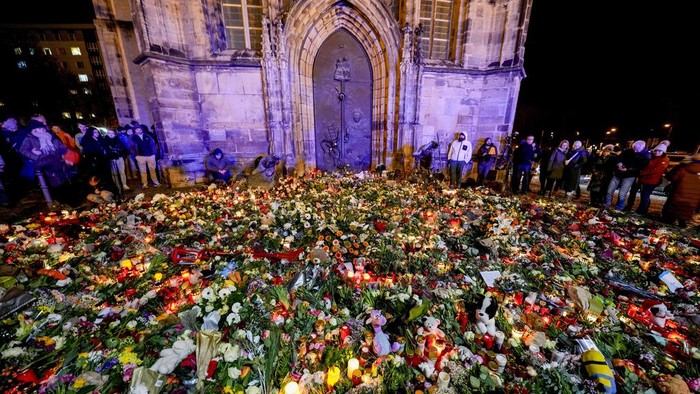 Lautan Bunga Kenang Korban Serangan Pasar Natal di Jerman Flowers and candles blanket the entrance to the Johannis church in tribute to the victims of a Christmas market attack where a car drove into shoppers the day before, in Magdeburg, Germany, Dec. 21, 2024. (AP Photo/Michael Probst)