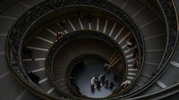 Turis berjalan-jalan di tangga Bramante di Museum Vatikan saat atap kaca fotovoltaik baru di pintu masuk diresmikan.