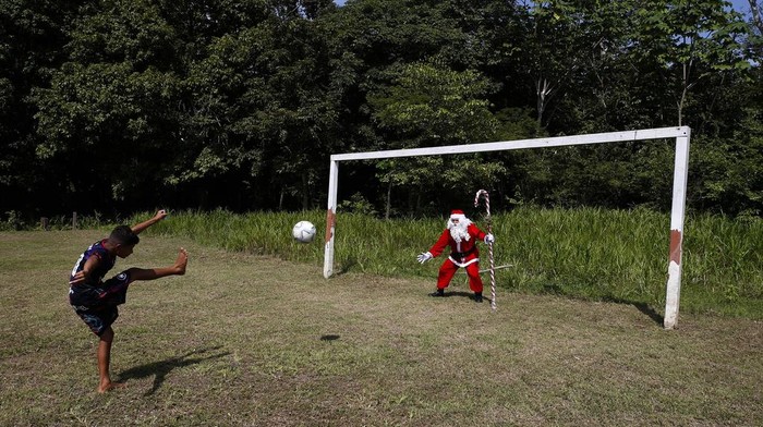 Jorge Barroso, dressed as Santa Claus, waves as he arrives on a boat to distribute Christmas gifts to children who live in the riverside communities of the Amazon, in Iranduba, Brazil, Saturday, Dec. 21, 2024. (AP Photo/Edmar Barros)