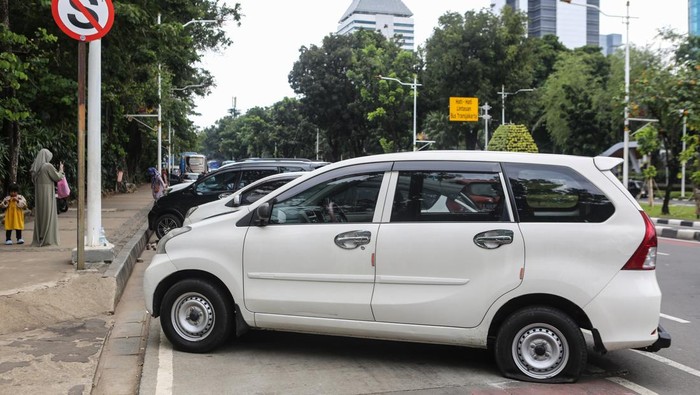 Sejumlah kendaraan yang telah dikempiskan bannya karena melanggar peraturan parkir di Jalan Medan Merdeka Selatan, kawasan Monumen Nasional (Monas), Jakarta, Minggu (29/12/2024). Petugas Dishub DKI Jakarta mengempiskan puluhan ban kendaraan yang kedapatan melanggar aturan karena parkir di bahu Jalan Medan Merdeka Selatan sesuai dengan Peraturan Daerah Provinsi DKI Jakarta Nomor 5 tahun 2012. ANTARA FOTO/Asprilla Dwi Adha/tom.
