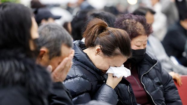 Keluarga penumpang pesawat yang jatuh setelah keluar landasan, bereaksi di Bandara Internasional Muan, di Muan, Korea Selatan, 29 Desember 2024. (REUTERS/Kim Soo-hyeon)