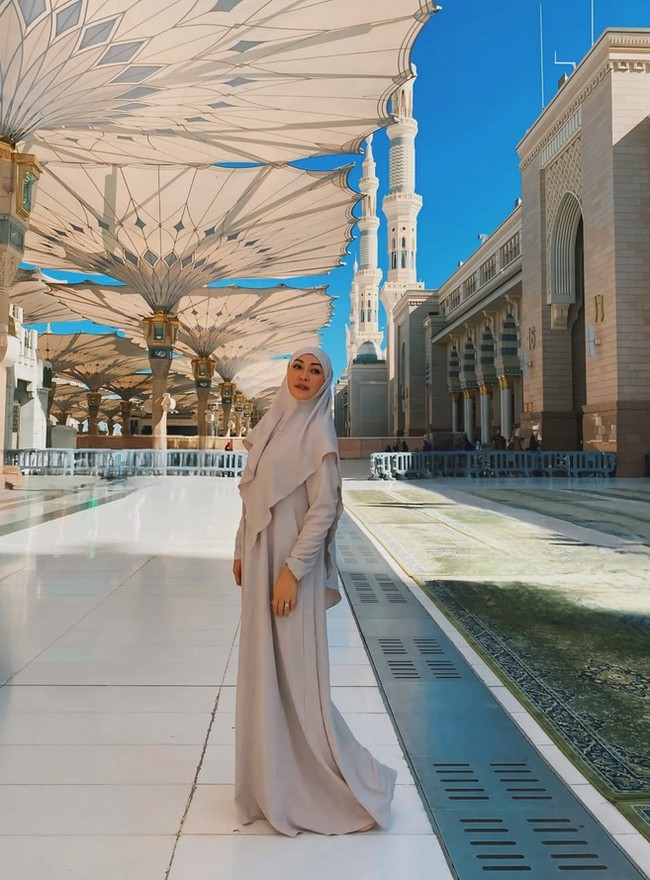 Pada saat di Madinah, wanita kelahiran 28 Desember 1977 memakai setelan khimar dan dress warna nude dari Si.Se.Sa. Angie membentuk tali khimar dimasukkan ke dalam kepala. Ia tak henti mengucap syukur bisa beribadah ke Tanah Suci. Semoga kita semua diberi kesempatan untuk melangkah ke tempat ini, mencium tanahnya, dan merasakan kedamaian yang tak tergantikan. Hidup terlalu singkat untuk menunda menjadi hamba yang dicintai-Nya. Mari pulang, dengan hati yang bersih dan penuh cinta.🤍🤍🤍, tulisnya. Foto: Dok. Instagram @angelinasondakh09.