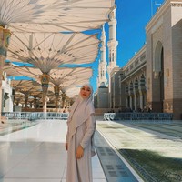 Pada saat di Madinah, wanita kelahiran 28 Desember 1977 memakai setelan khimar dan dress warna nude dari Si.Se.Sa. Angie membentuk tali khimar dimasukkan ke dalam kepala. Ia tak henti mengucap syukur bisa beribadah ke Tanah Suci. Semoga kita semua diberi kesempatan untuk melangkah ke tempat ini, mencium tanahnya, dan merasakan kedamaian yang tak tergantikan. Hidup terlalu singkat untuk menunda menjadi hamba yang dicintai-Nya. Mari pulang, dengan hati yang bersih dan penuh cinta.🤍🤍🤍, tulisnya. Foto: Dok. Instagram @angelinasondakh09.